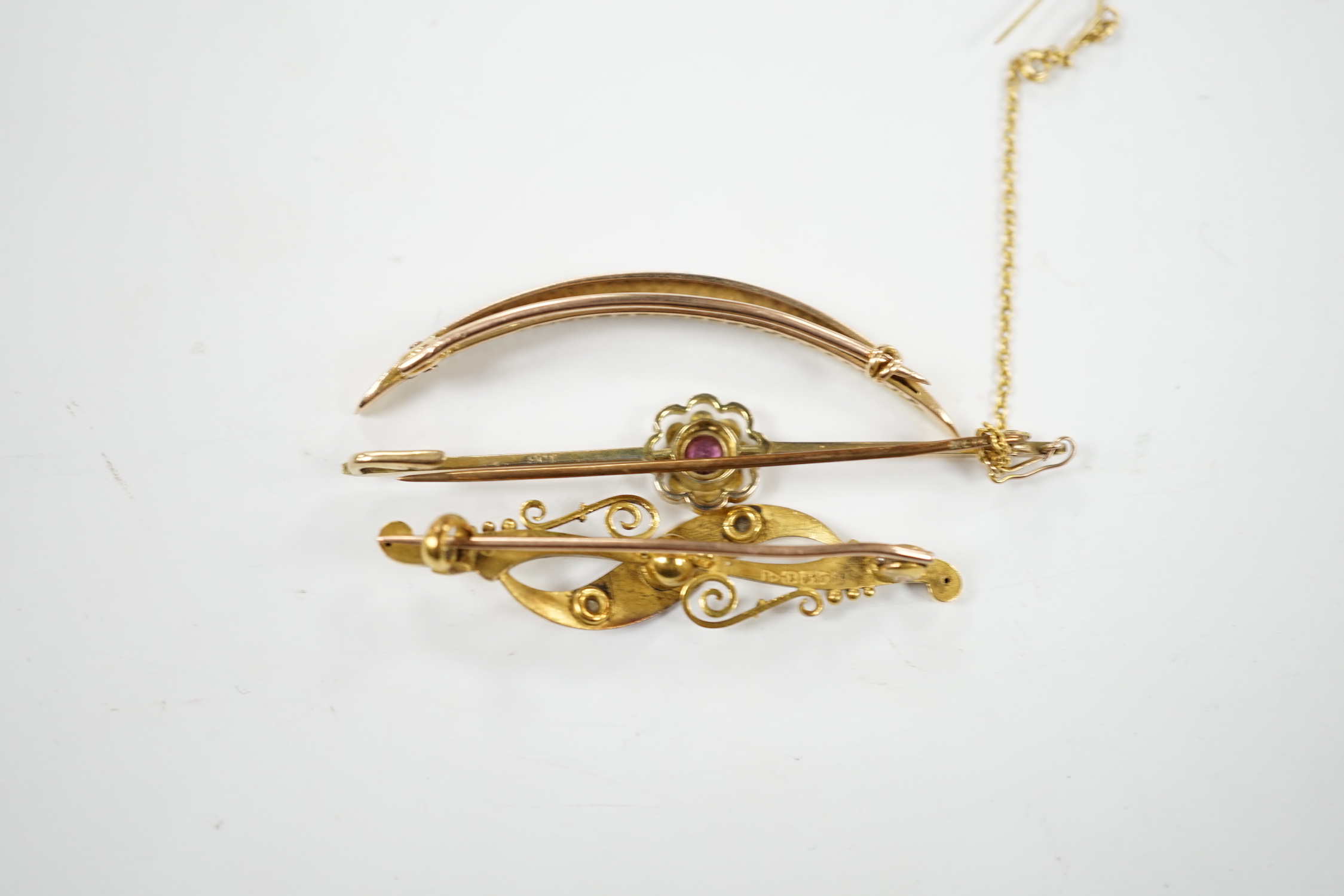 An Edwardian 15ct, ruby and diamond chip set three stone bar brooch, 45mm, a 9ct and gem set bar brooch and a yellow metal and seed pearl set crescent brooch.